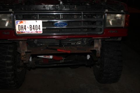 1990 Ford Bronco - Front view of a red Ford Bronco with a custom bumper and tools, showing the grille and headlights.