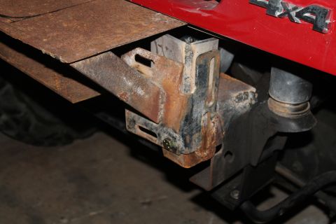 1990 Ford Bronco - Close-up of a rusty bumper mount on a red vehicle with a 4x4 badge.