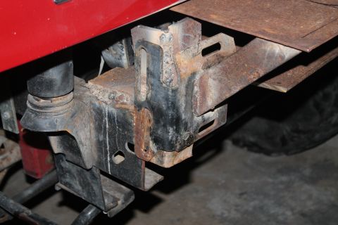 1990 Ford Bronco - Close-up view of a red fender and the rusty bumper mounting bracket on a vehicle.