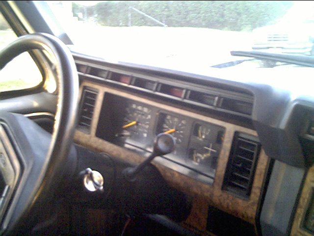 1980s Ford truck instrument cluster and woodgrain dash seen from the driver's seat