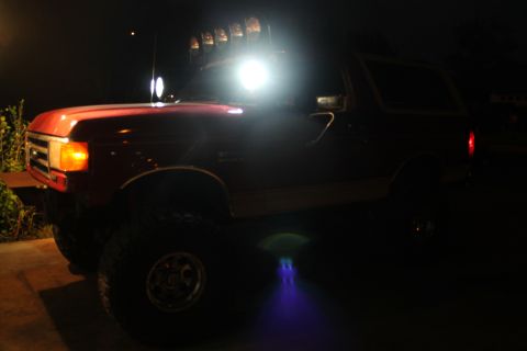 1990 Ford Bronco - A red 1990 Ford Bronco is illuminated by its own lights and underglow at night.