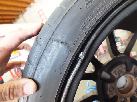 2003 Ford Crown Victoria - Fingers indicate a scuff on a tire sidewall beside a black wheel and rusted brake hub.