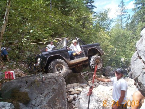 1977 Ford Bronco - A black 1977 Ford Bronco navigates a challenging rocky trail with assistance from onlookers.