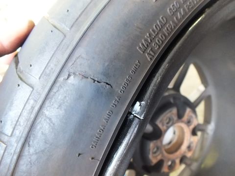 2003 Ford Crown Victoria - Tire sidewall crack shown in detail; stamped load ratings and a corroded hub appear in the frame.