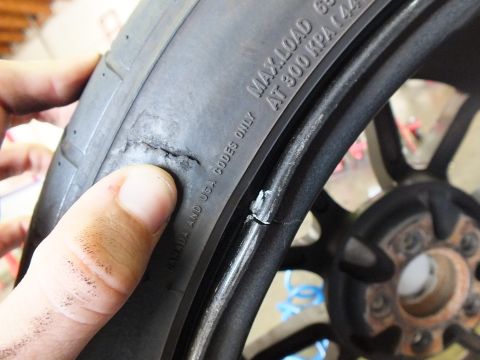 2003 Ford Crown Victoria - Close shot of a tire sidewall blemish; a hand steadies the tire against a black wheel and hub.