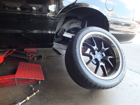 2003 Ford Crown Victoria - Low-angle view of a black sedan on a shop lift; rear suspension and a wide tire are exposed.