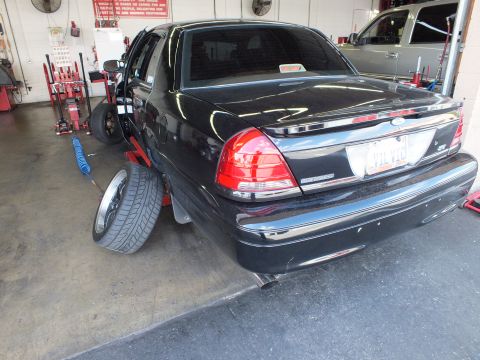 2003 Ford Crown Victoria - Rear of a black Ford Crown Victoria in a garage; a spare wheel rests against the rear bumper.