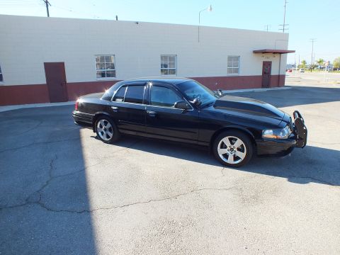 2003 Ford Crown Victoria - Side front view of a lowered black Crown Victoria with a brush guard parked by a white building.