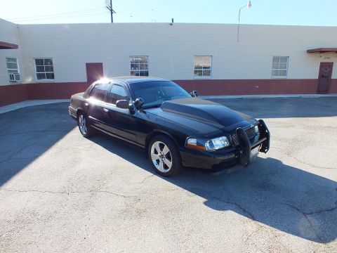 2003 Ford Crown Victoria - Black Crown Victoria with grille guard parked outside a building; amber markers and tinted windows.