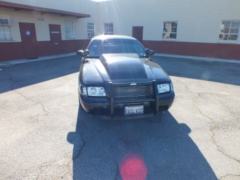 2003 Ford Crown Victoria - Front view of a black Crown Victoria fitted with a push bumper; vanity plate reads EVIL VIC.