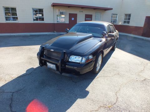 2003 Ford Crown Victoria - Front three-quarter view of a blacked-out Crown Victoria sedan fitted with a chrome push bar in a parking lot.