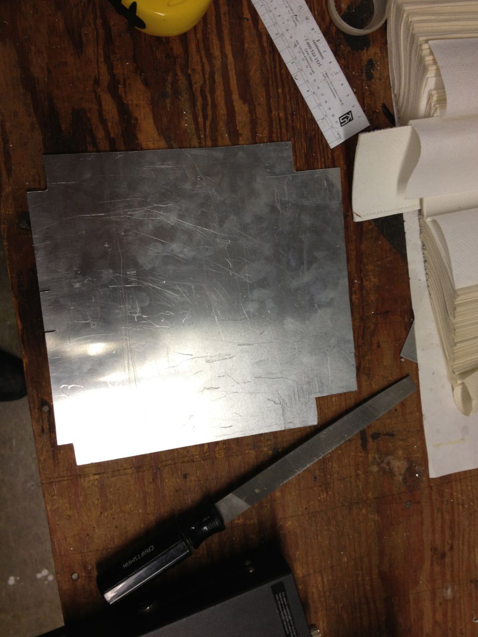 Sheet metal cut to shape with a file and ruler on a wooden workbench