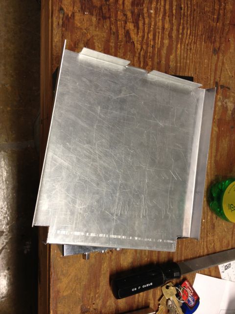 1979 Ford Bronco - A metal panel with visible scratches and folded edges is shown on a wooden table.