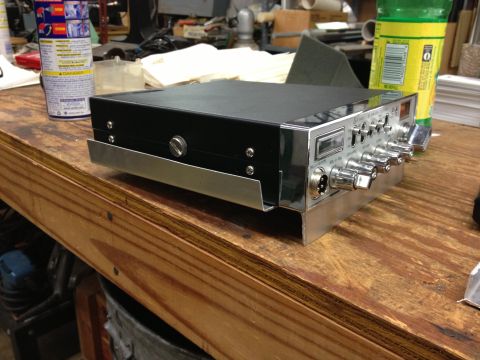 1979 Ford Bronco - A close-up view of a CB radio unit sitting on a wooden surface, with various controls and a small screen visible.