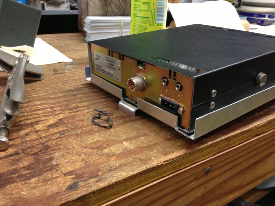 CB radio with rear connectors and a label, on a wooden surface with tools