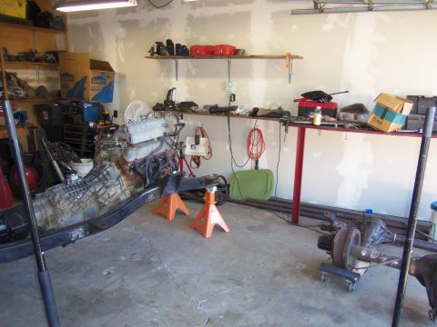 1968 Ford Bronco - An engine and transmission assembly is supported by jack stands in a workshop setting, surrounded by tools and parts.