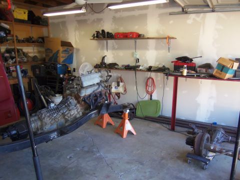 1968 Ford Bronco - Garage scene with engine and transmission on jack stands, parts on shelves, and tools.