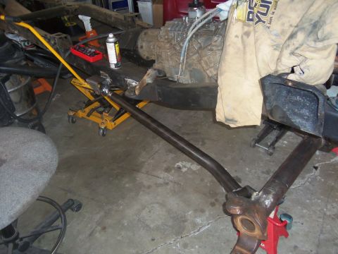 1968 Ford Bronco - Vehicle chassis and drivetrain components are supported by jacks in a garage setting.
