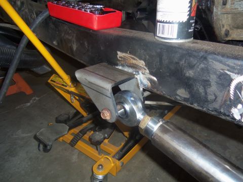 1968 Ford Bronco - Close-up of a vehicle's frame undergoing modification with a new suspension part and jack support.