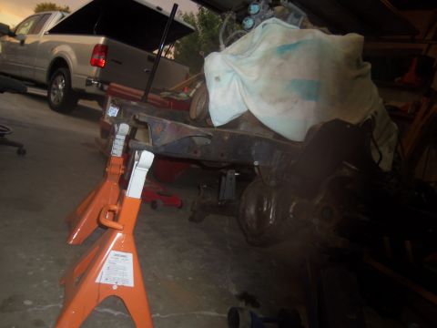 1968 Ford Bronco - Frame and suspension parts are elevated on jack stands, with a pickup truck visible behind.