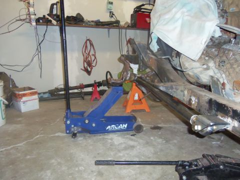 1968 Ford Bronco - The vehicle frame is supported by jack stands in a cluttered garage environment.