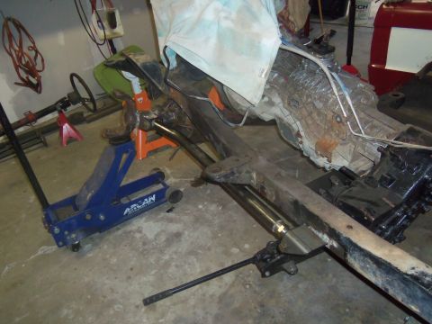 1968 Ford Bronco - Vehicle frame and transmission assembly supported by jacks in a garage setting.