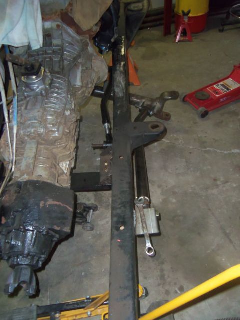 1968 Ford Bronco - A vehicle's transmission and part of its frame are shown in a workshop setting with tools on the floor.