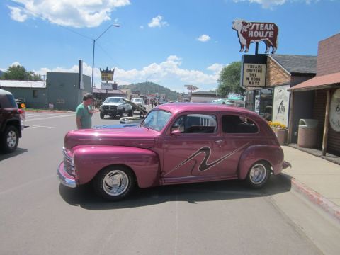 1991 Ford LTD Crown Victoria - A pink sedan with custom graphics is parked on a street, with other vehicles and buildings in the background.