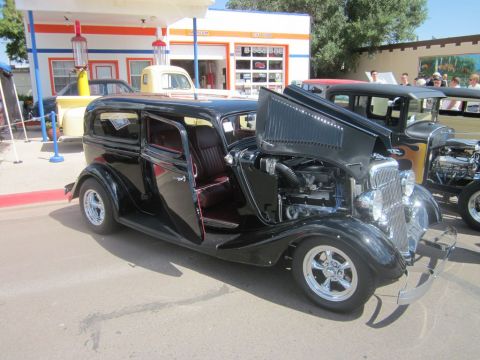 1991 Ford LTD Crown Victoria - A classic hot rod sedan is displayed with its engine exposed, parked in front of a vintage gas station.