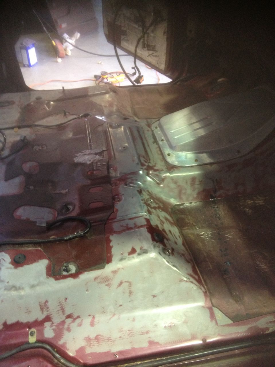Vehicle interior floor with red and white paint, exposed metal, and wiring