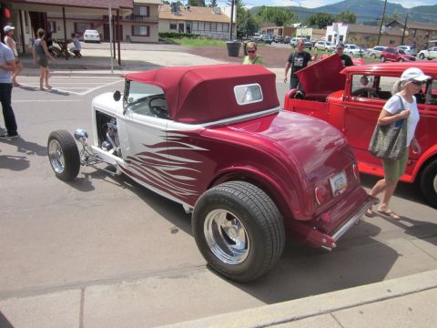 1991 Ford LTD Crown Victoria - A custom hot rod convertible and a red sedan are on display at an outdoor car show.