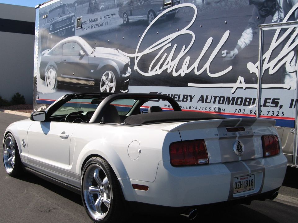 White convertible 2007 Ford Mustang with racing stripes and Shelby badging