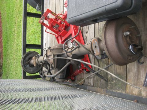 1994 Ford Bronco - A disassembled rear axle assembly is shown, resting on a wooden platform with a red jack.