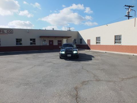 2003 Ford Crown Victoria - Front-on distant view of the black Ford in a large empty lot under a blue sky.