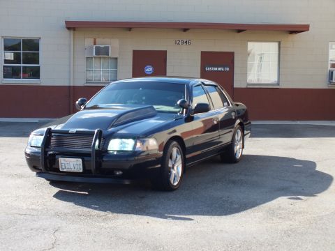 2003 Ford Crown Victoria - Front-left view of the modified black sedan with grille push bar and lit headlights.
