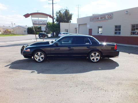 2003 Ford Crown Victoria - Side view of the black sedan showing push bar, hood scoop and polished wheels.