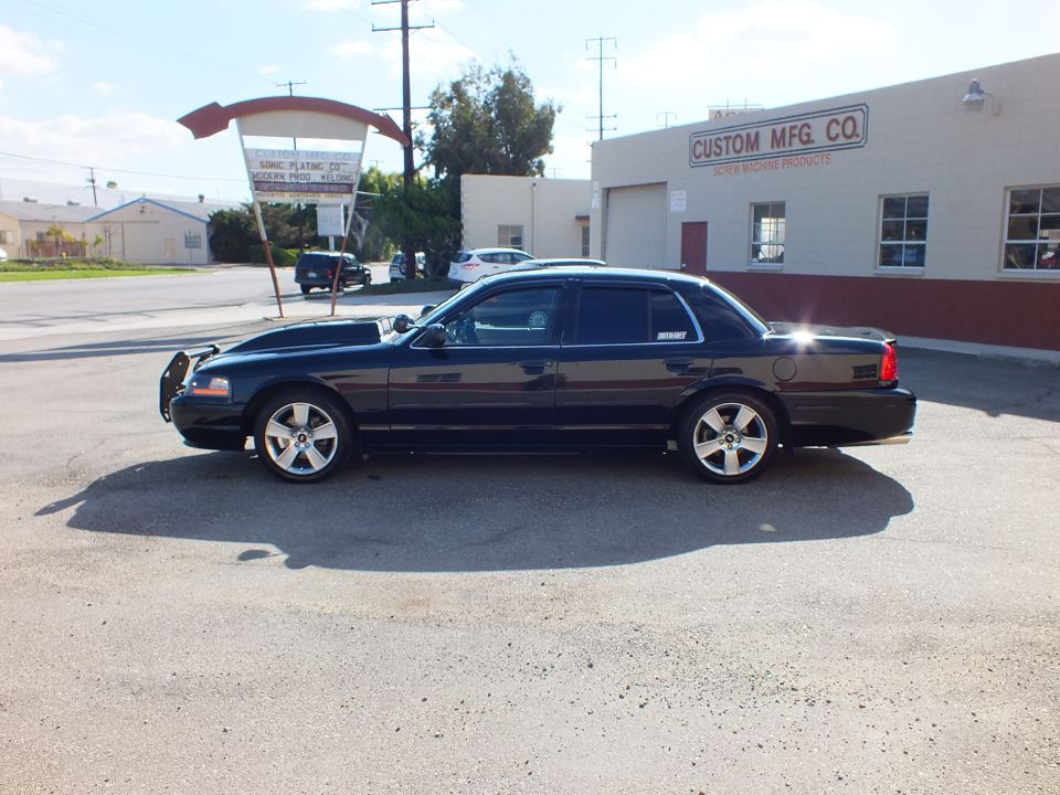 Left profile of black Ford Crown Victoria with chrome wheels by Custom Mfg. Co.