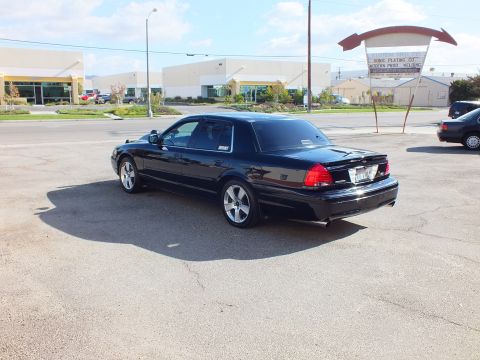 2003 Ford Crown Victoria - Rear three-quarter shot of the black Crown Victoria parked across an open lot.