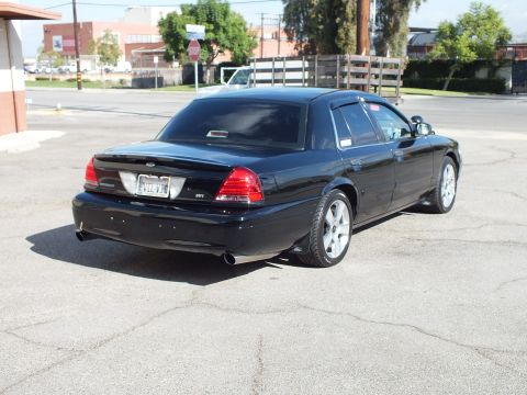 2003 Ford Crown Victoria - Rear quarter of a black full-size sedan showing trunk lip, taillights and rear tire camber in an industrial lot.
