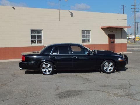 2003 Ford Crown Victoria - Profile of a black Mercury Marauder with chrome wheels and low ride height in a parking lot.