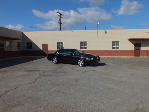 2003 Ford Crown Victoria - Distant front-quarter view of a black Mercury Marauder in a cracked asphalt lot.