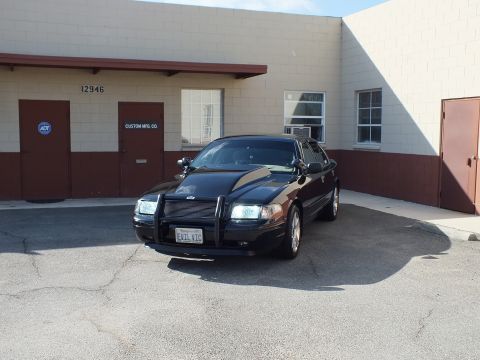 2003 Ford Crown Victoria - Front of a black full-size sedan with push bar parked at Custom Mfg Co loading bay, EVIL VIC plate.