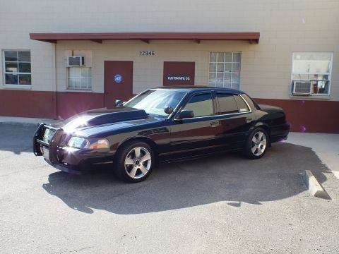 2003 Ford Crown Victoria - Front quarter of a black sedan with push bar, sunlight glinting off bumper, at Custom Mfg Co.