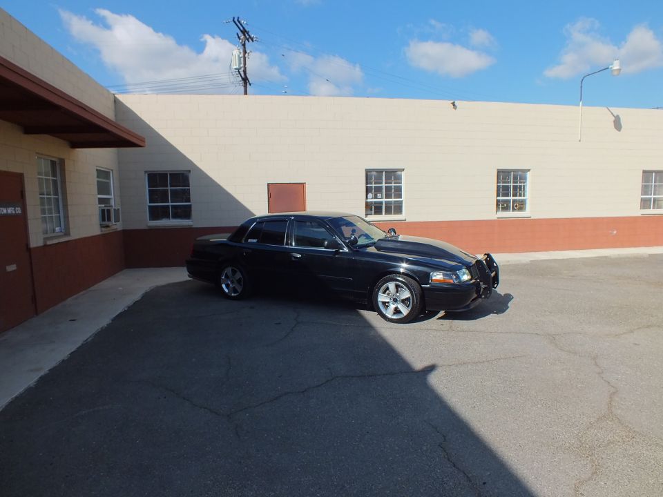 Black Mercury Marauder passenger side profile with door mirror folded, parked by tan building