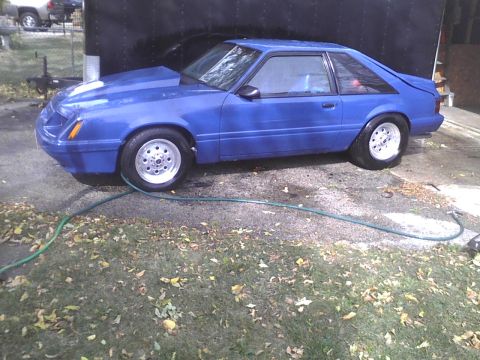 2003 Ford Crown Victoria - Blue coupe with aftermarket hood and drag wheels is parked outside.