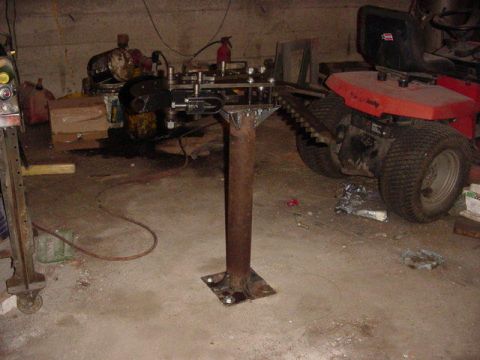 1992 Ford Bronco - A red lawn tractor is parked next to a homemade metal fabrication stand in a cluttered garage.