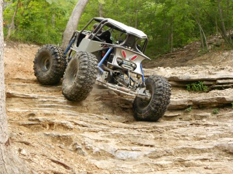 1967 Ford Mustang - A custom-built buggy navigates a challenging rocky trail in a wooded area.