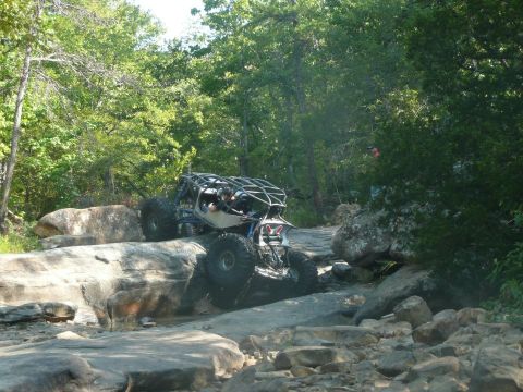 1967 Ford Mustang - Custom buggy crawling over rocks on a wooded trail.