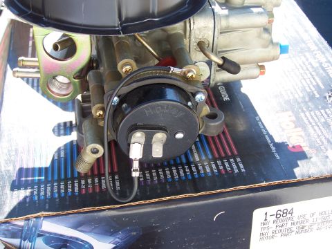 1991 Ford LTD Crown Victoria - A Holley carburetor is shown close-up, resting on a box with a parts guide visible underneath.
