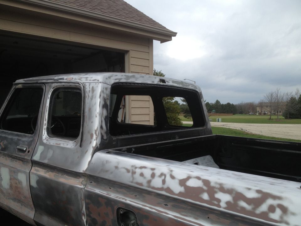 pickup truck body, primer showing, parked outside garage
